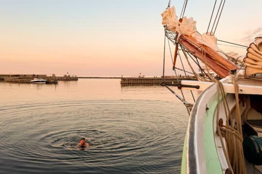 Aron guest swimming off bow at sunset in Scandinavia