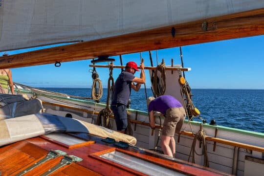 Aron guests onboard pulling ropes on deck sailing in Scandinavia