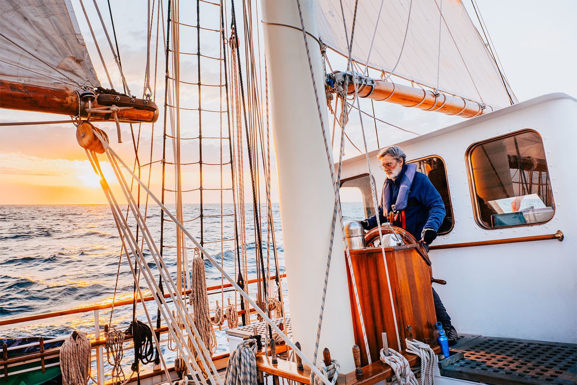 Blue Clipper guest at helm at sunset tall ship