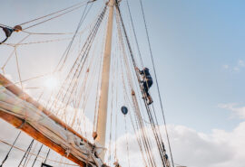 Blue Clipper guest climbing rigging on tall ship