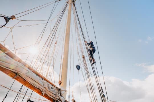 Blue Clipper guest climbing rigging on tall ship