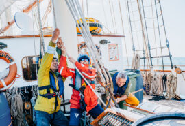 Blue Clipper guests pulling ropes on deck of tall ship