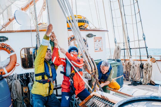 Blue Clipper guests pulling ropes on deck of tall ship