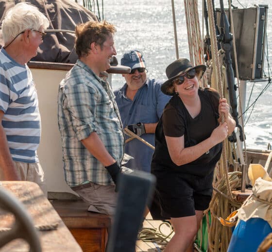 Blue Clipper guests raising the jib sails hands on tall ship