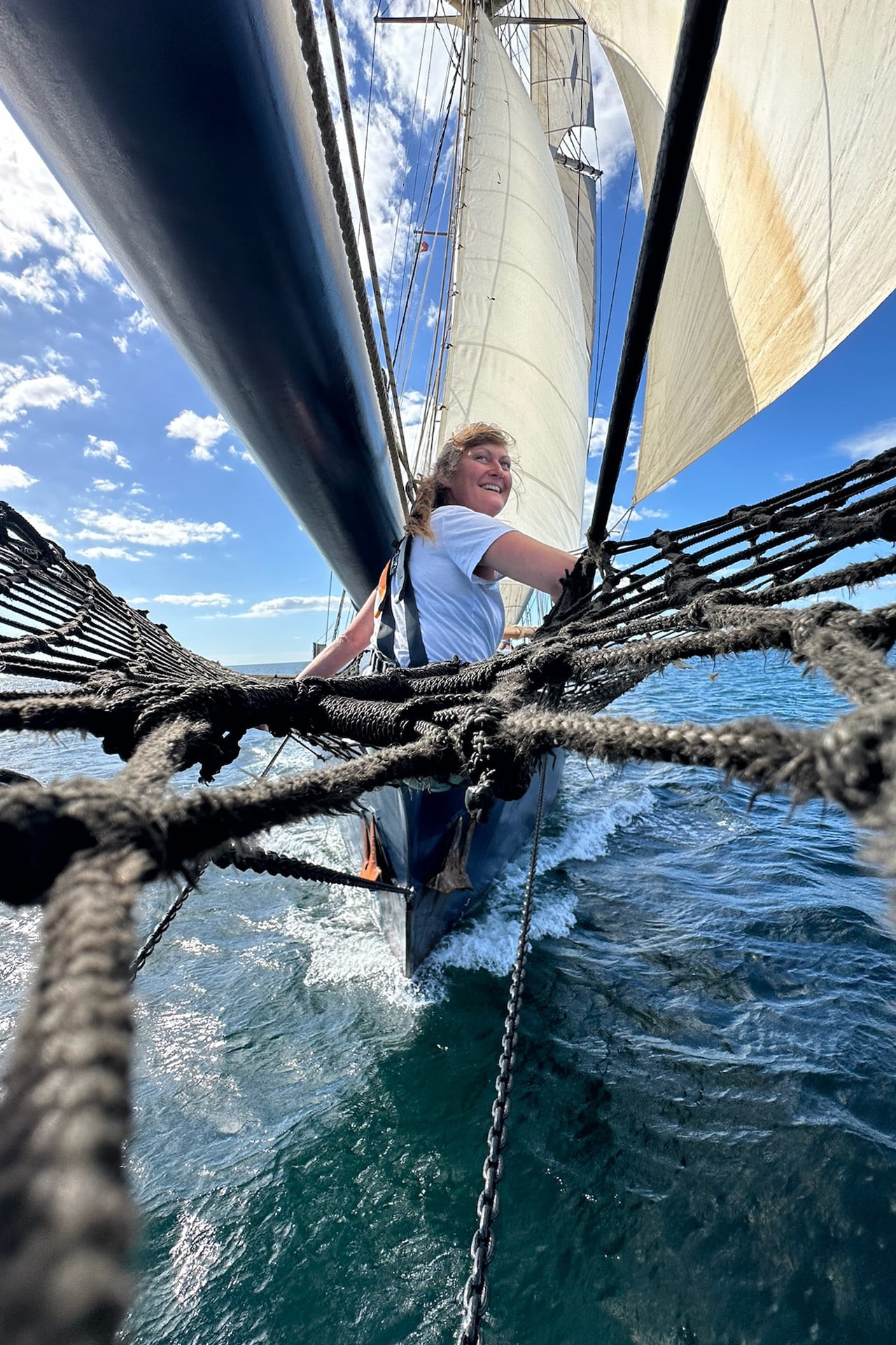 Blue Clipper tall ship guest on bowsprit sailing in Portugal
