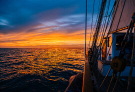 Blue Clipper tall ship on deck at sunset