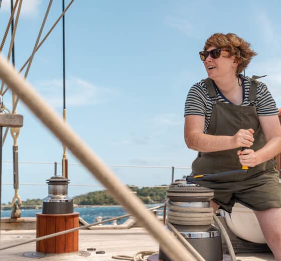 Chronos guest onboard working on the winches on deck female solo sailor