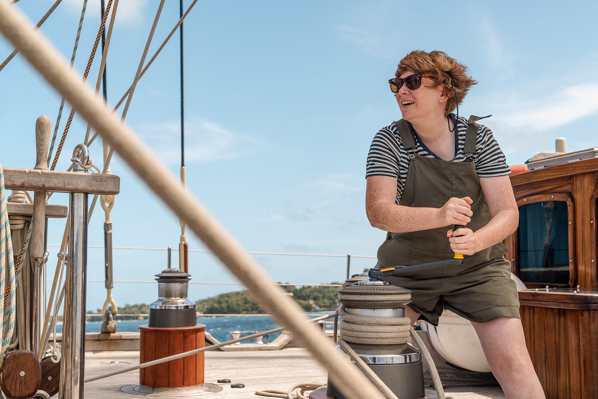 Chronos guest onboard working on the winches on deck female solo sailor