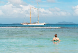 Chronos guest swimming with yacht anchored in background in Caribbean
