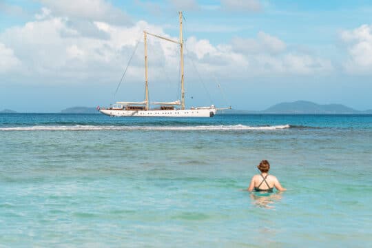 Chronos guest swimming with yacht anchored in background in Caribbean