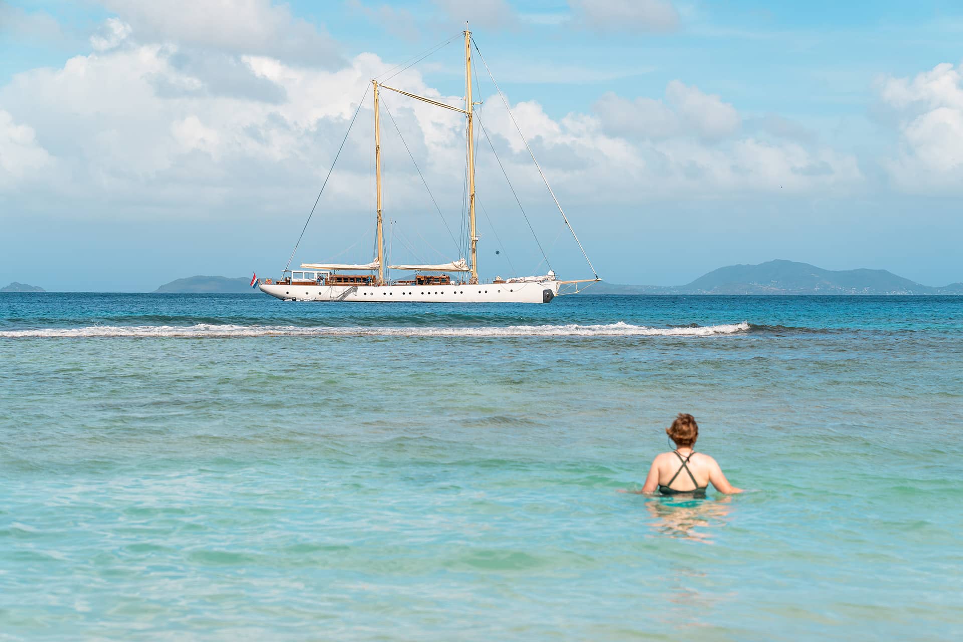 Chronos guest swimming with yacht anchored in background in Caribbean
