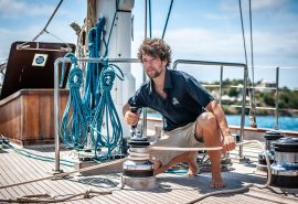 Crew member winching sails on board SC Chronos Rhea Kairos