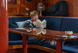 Flying Dutchman Guest onboard reading and relaxing in the saloon
