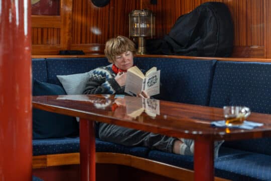 Flying Dutchman Guest onboard reading and relaxing in the saloon