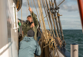 Flying Dutchman guests onboard raising the sails pulling ropes