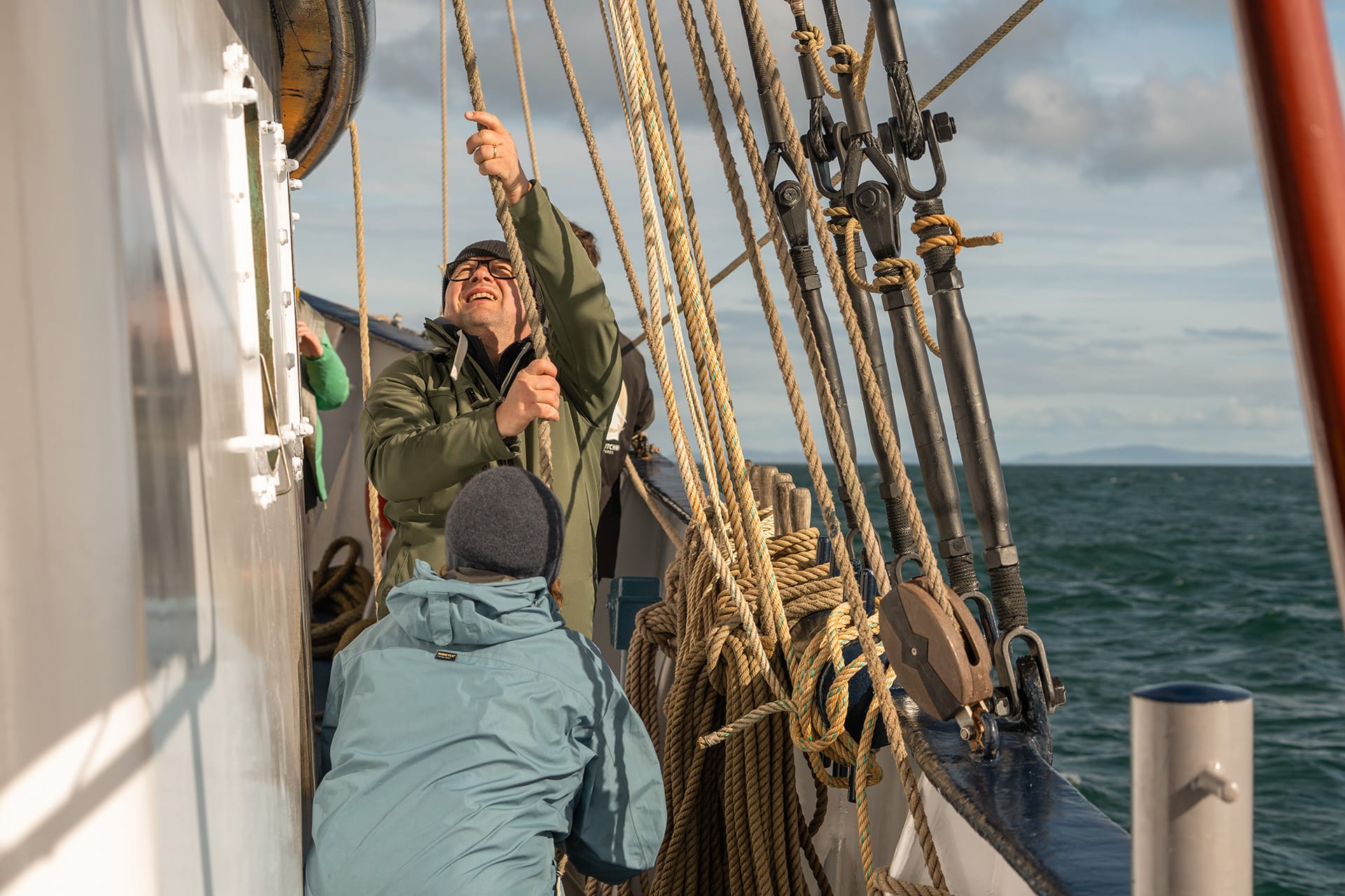 Flying Dutchman guests onboard raising the sails pulling ropes