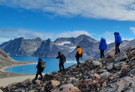 Guests hiking in Greenland with Valiente anchored