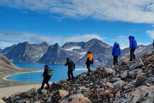 Guests hiking in Greenland with Valiente anchored