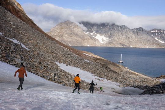 Guests hiking in Greenland with Valiente anchored