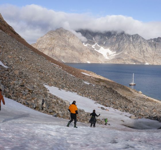 Guests hiking in Greenland with Valiente anchored