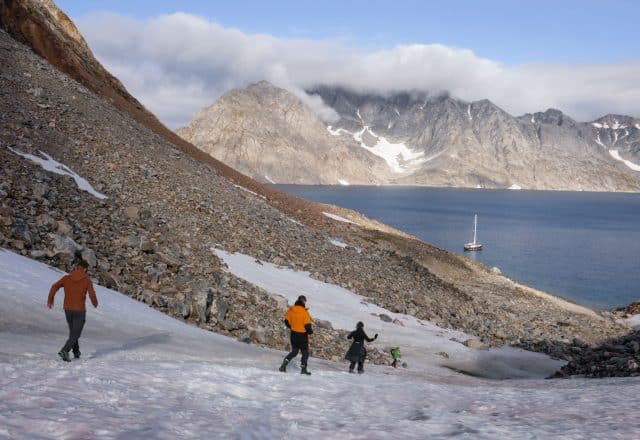 Guests hiking in Greenland with Valiente anchored