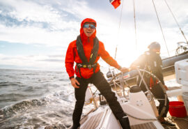 Humla guests sailing underway at helm in Lofoten islands, Norway, adventure