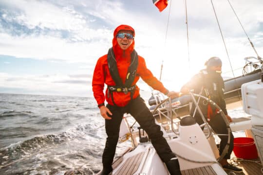 Humla guests sailing underway at helm in Lofoten islands, Norway, adventure