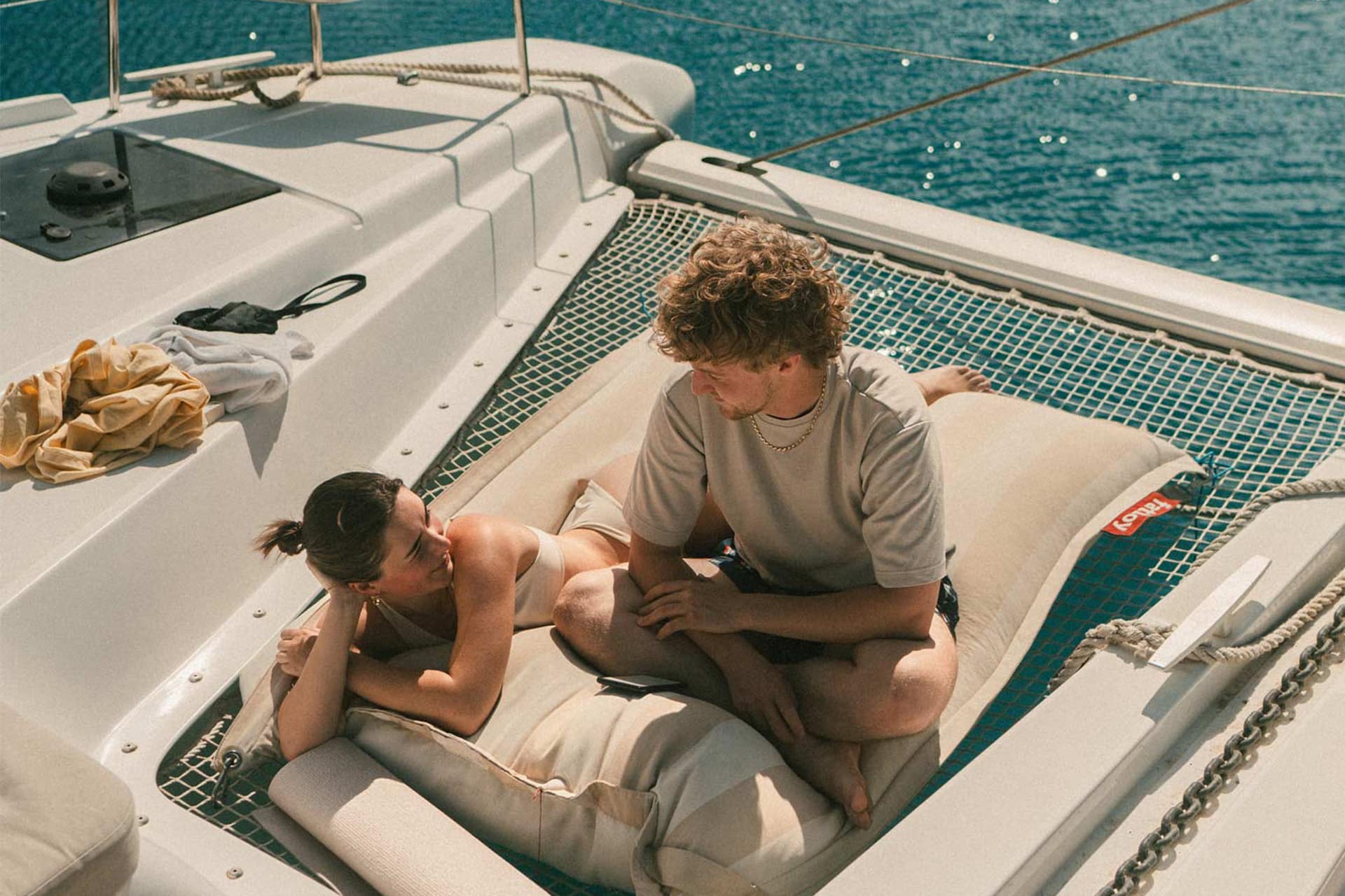 Ingrid More catamaran guests relaxing on nets onboard summers day