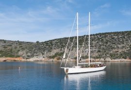 Kairos anchored with guest paddleboarding in the Mediterranean