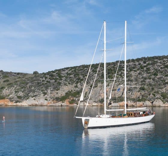 Kairos anchored with guest paddleboarding in the Mediterranean