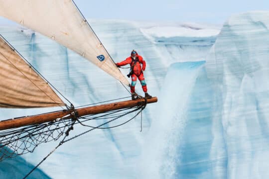 Linden expedition leader Joe onboard on bowsprit in the Arctic Greenland