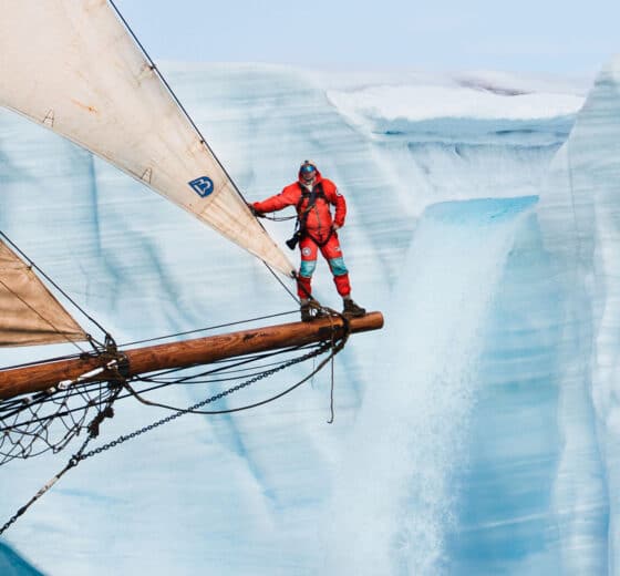 Linden expedition leader Joe onboard on bowsprit in the Arctic Greenland