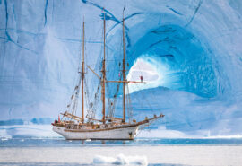 Linden tall ship anchored beneath glacier in Greenland Arctic Circle sailing