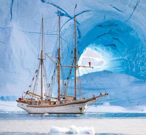 Linden tall ship anchored beneath glacier in Greenland Arctic Circle sailing
