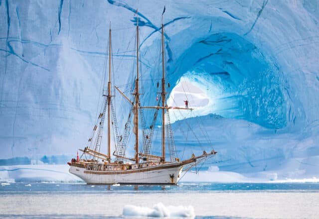 Linden tall ship anchored beneath glacier in Greenland Arctic Circle sailing