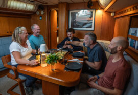 Noonmark VI adventure yacht below deck interior guests enjoying meal onboard dining dinner