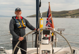 Noonmark VI guest onboard at helm male solo sailor traveller sailing