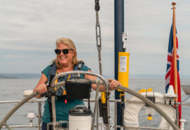 Noonmark VI guest onboard at helm solo female sailor in Scotland, Hebrides sailing