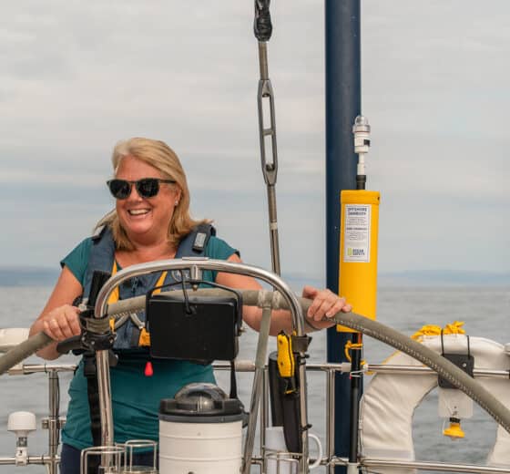Noonmark VI guest onboard at helm solo female sailor in Scotland, Hebrides sailing