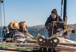 Noonmark VI guests with skipper at helm sailing in Scotland