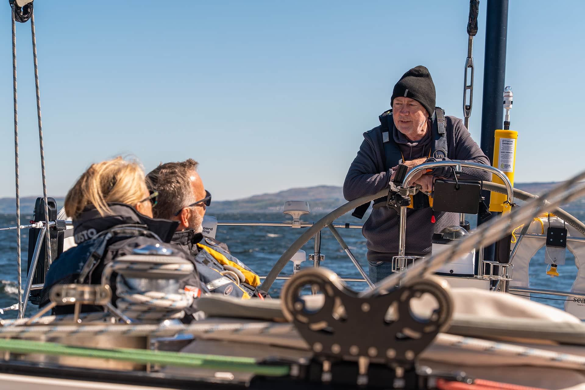 Noonmark VI guests with skipper at helm sailing in Scotland