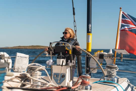 Noonmark VI yacht guest at helm solo female sailor JO