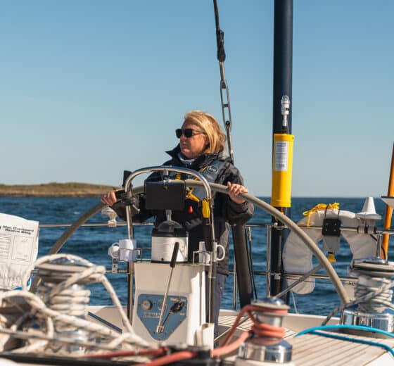 Noonmark VI yacht guest at helm solo female sailor JO