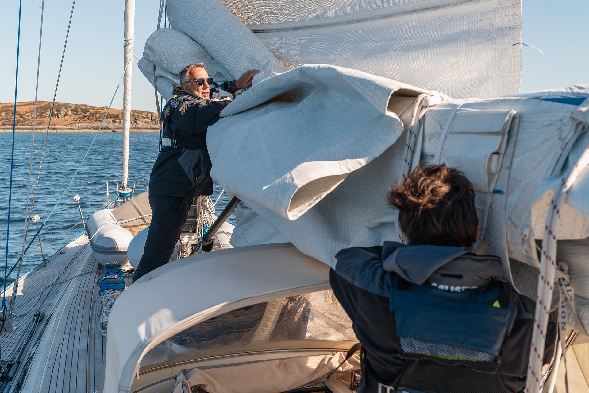 Noonmark VI yacht guests furling sails sailing in scotland