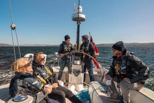 Noonmark VI yacht guests underway on deck at helm