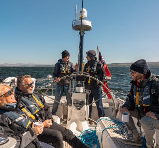 Noonmark VI yacht guests underway on deck at helm
