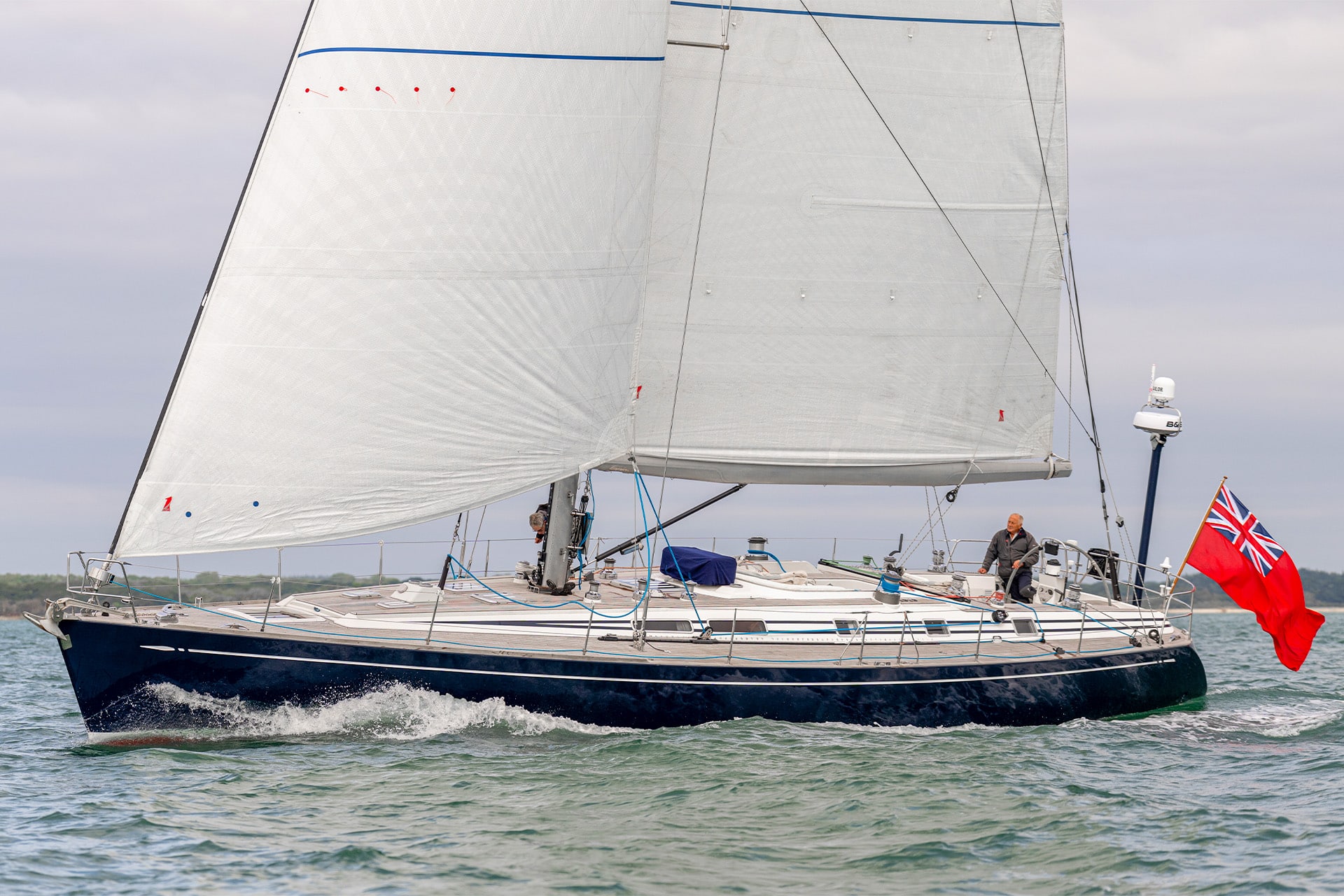 Noonmark VI yacht sailing underway from side coastline