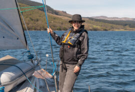 Noonmark VI yacht solo female guest on deck of yacht underway sailing in Scotland