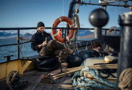 Noorderlicht tall ship guests relaxing reading on deck in Arctic Svalbard