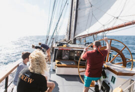 Twister guests on deck at helm sailing underway